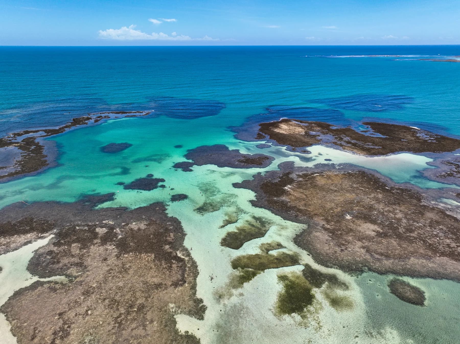 Recifes e piscinas naturais de águas transparentes vistos do alto em Boipeba