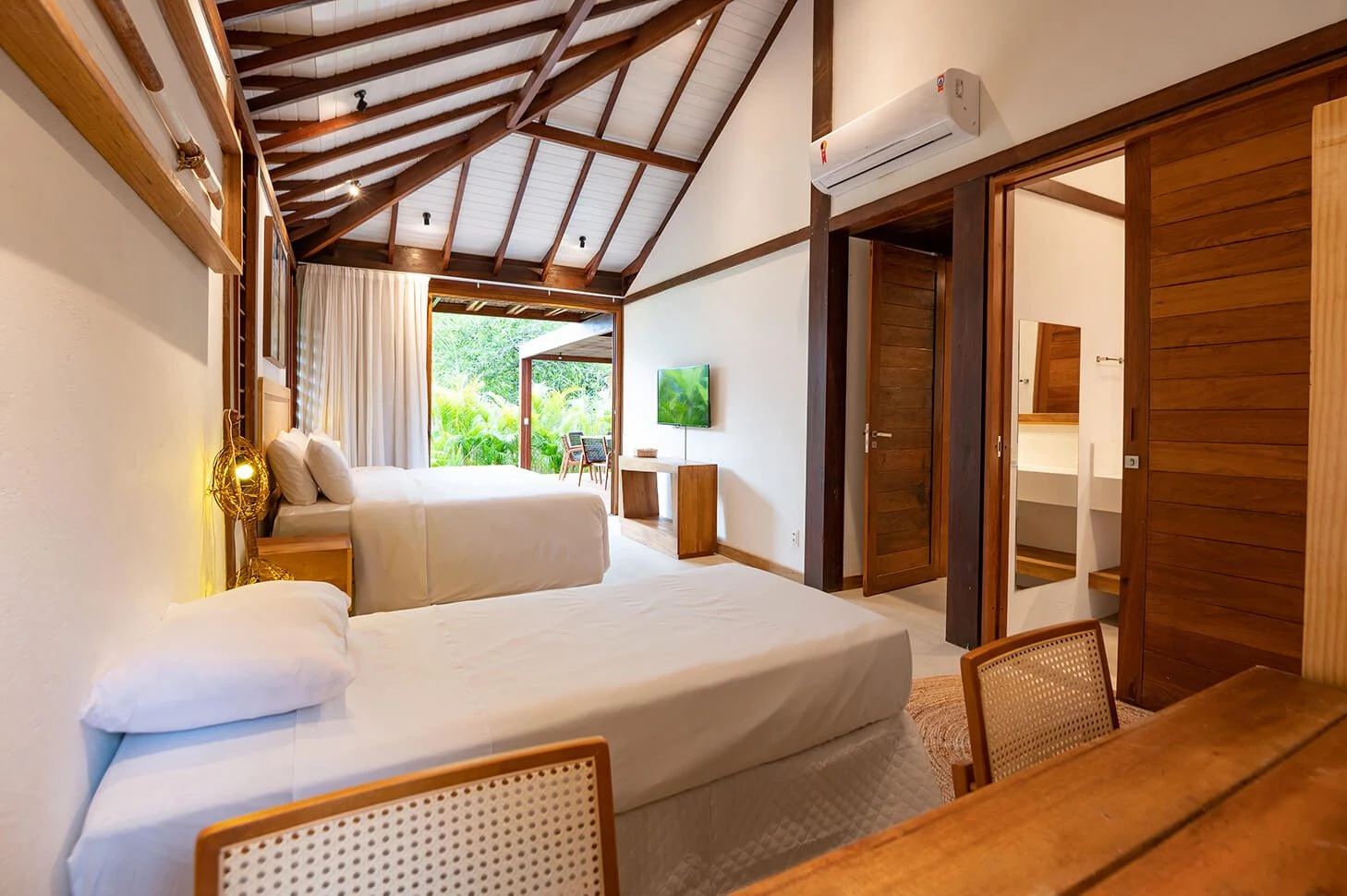Quarto da Villa 1 com camas, teto alto de madeira e abertura para o jardim